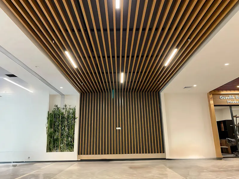 Ahşap desenli baffle tavan ve aynı panellerle kaplanmış duvar, lineer aydınlatmalı hol